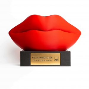 Trophée personnalisé en impression 3D filament représentant une sculpture de lèvres rouges sur socle noir avec plaque personnalisée, fabrication française.